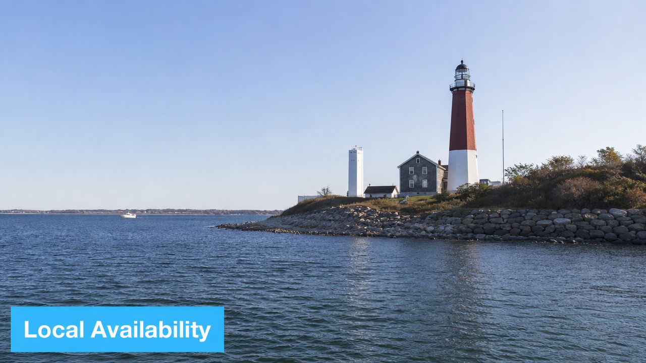 The Montauk Point Lighthouse stands prominently on a rocky coastline overlooking the blue Atlantic Ocean.